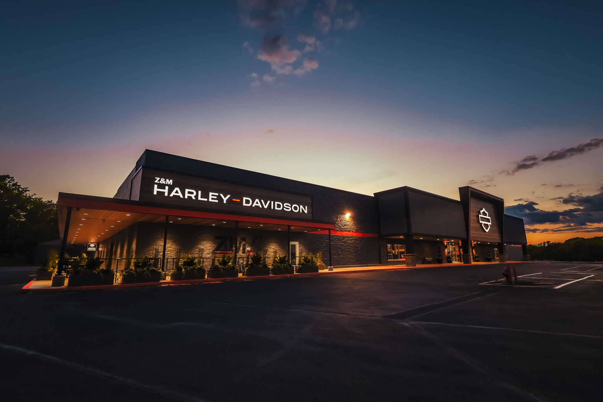 Z&M Harley-Davidson dealership exterior at dusk, with illuminated signage, timber facade and covered entrance